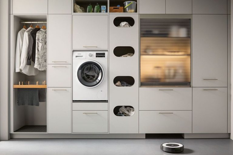 Hauswirtschaftsraum Moderner Waschraum mit hellen Schränken, Waschmaschine und Roboterstaubsauger.